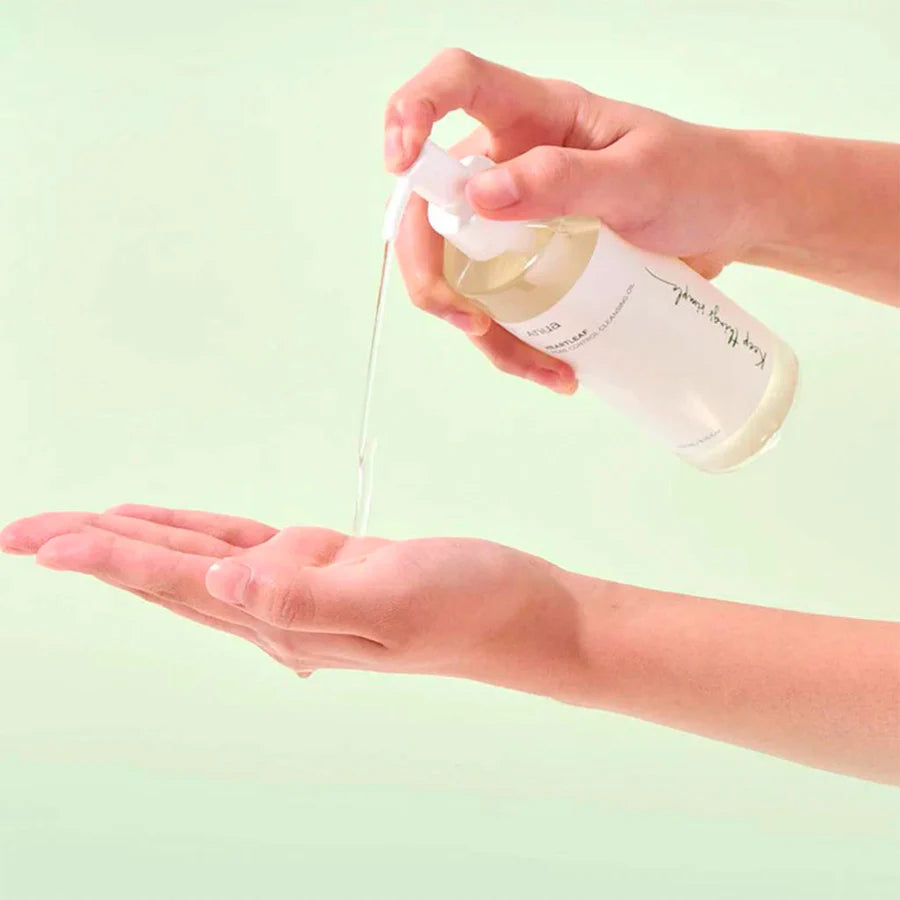 Anua heartleaf cleansing oil being dispensed from a clear pump bottle onto hand