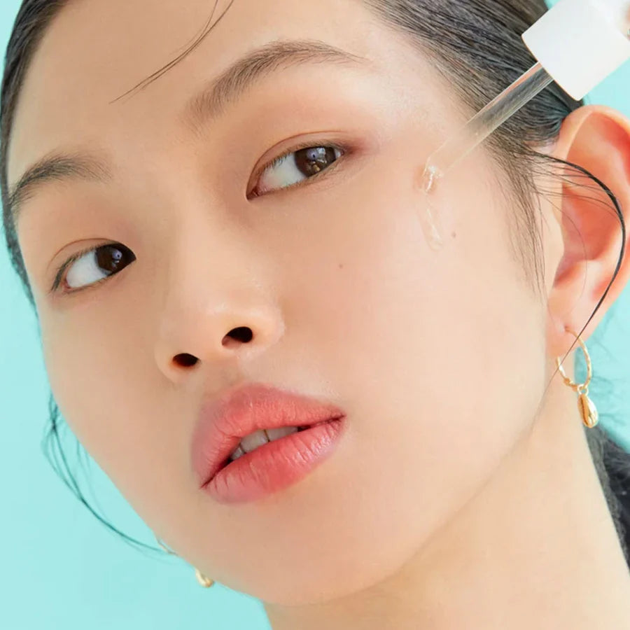 Close-up of woman applying AXIS-Y artichoke skin barrier ampoule on her cheek with dropper