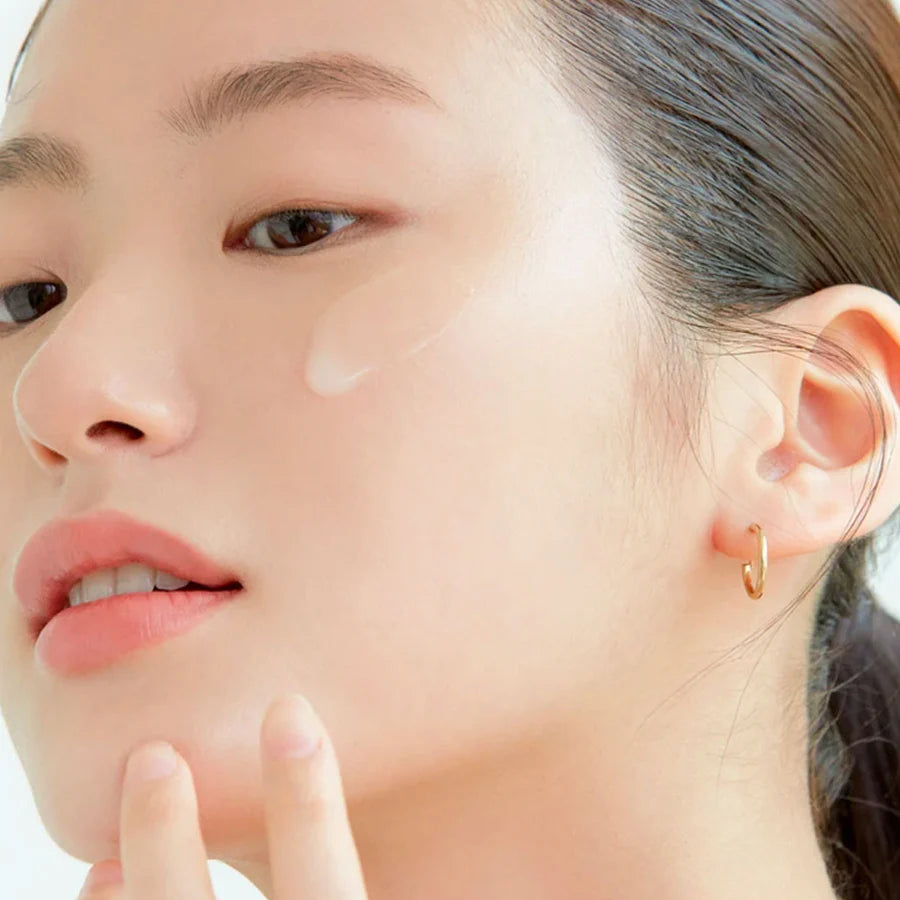 Close-up of woman applying AXIS-Y dark spot correcting serum on her cheek for clear skin