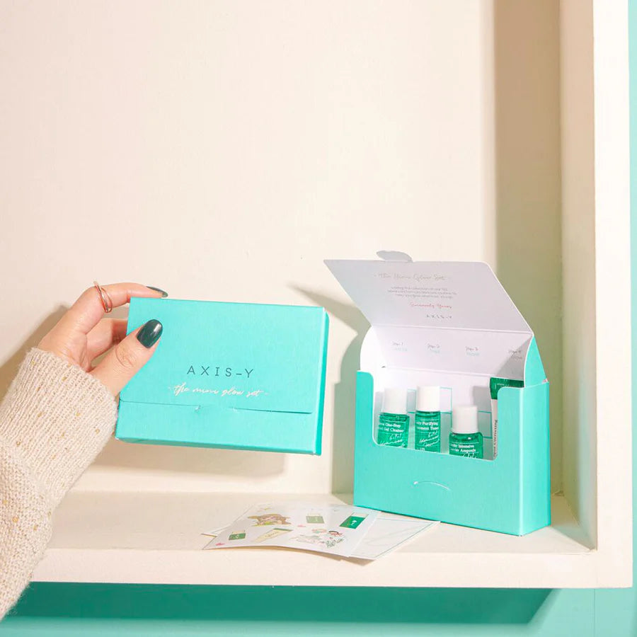 AXIS-Y Mini Glow Set skincare with three green bottles in teal box held by hand