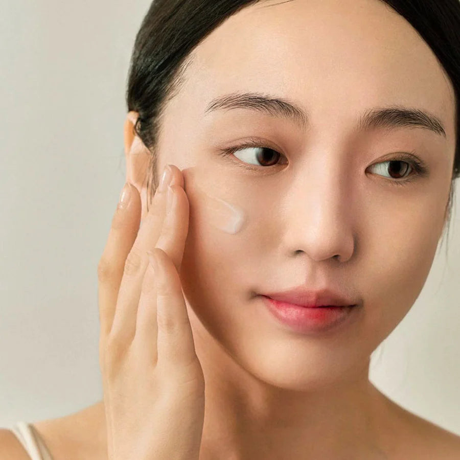 Woman applying Beauty Of Joseon centella vitamin c serum on her cheek for glowing skin