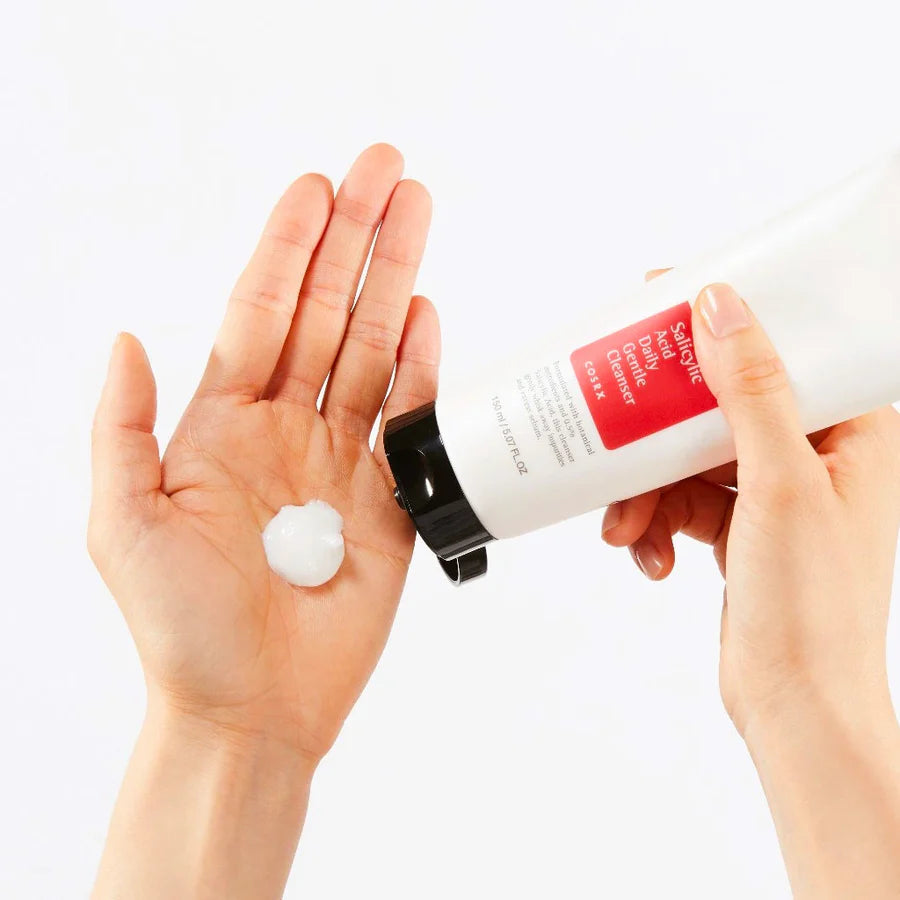 Cosrx salicylic acid facial cleanser being dispensed into a hand with white creamy texture
