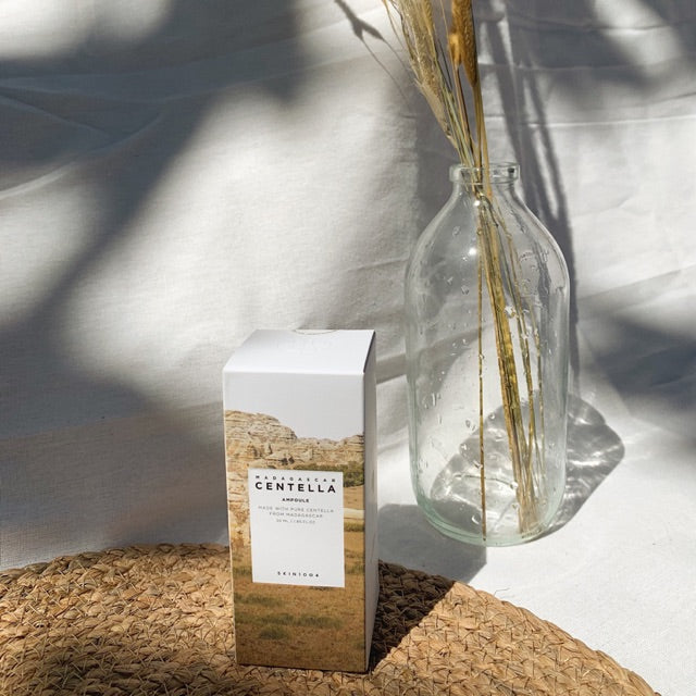 Skin1004 Madagascar Centella Asiatica ampoule box displayed next to clear glass vase with dried plants