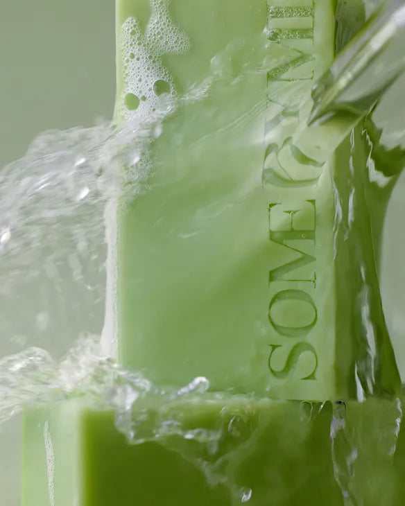 Some By Mi green AHA BHA PHA cleansing bar with water splashing on it for body cleansing